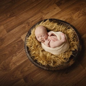 Newborn baby photographed on wooden floor